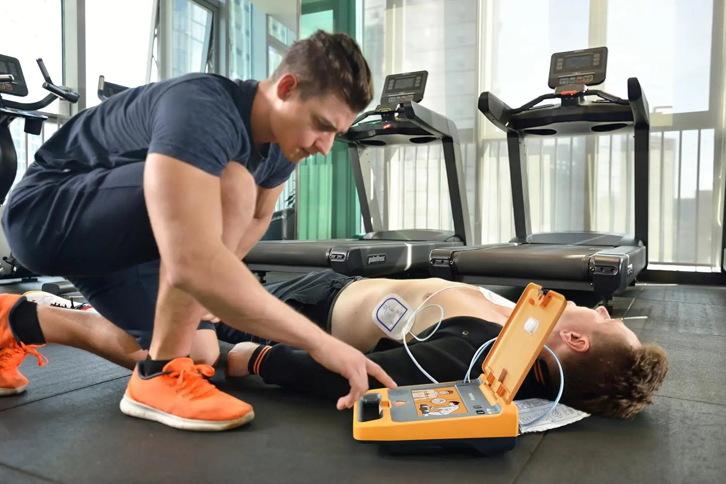 Person using defib on person in cardiac arrest in the gym