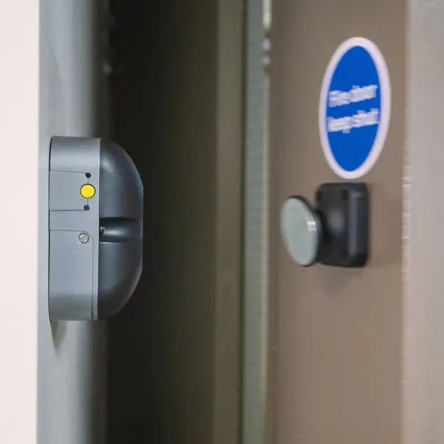 Close-up of a door handle and lock mechanism on a metal door with a blue sign.