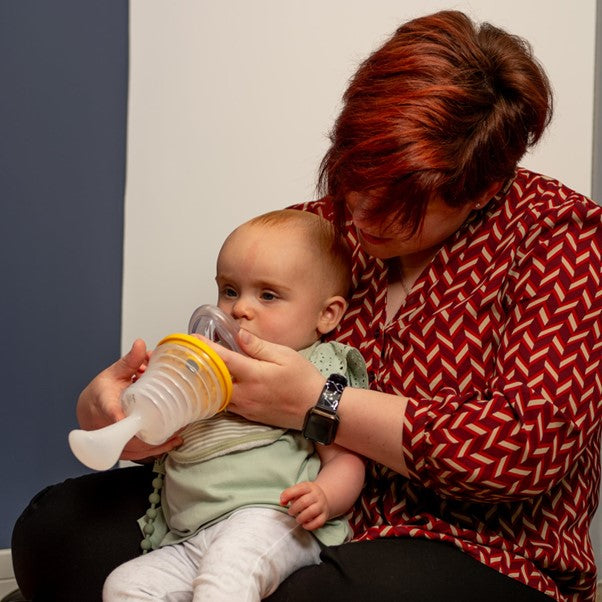 Woman holding a baby using breathing apparatus.