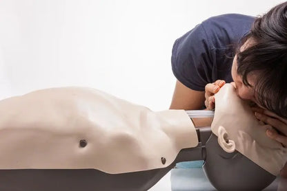 Person performing CPR on a mannequin with a white background