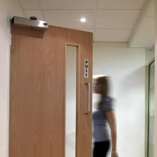 Wooden door with a pull handle in an indoor setting, blurred person in the background