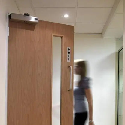 Wooden door with a pull handle in an indoor setting, blurred person in the background