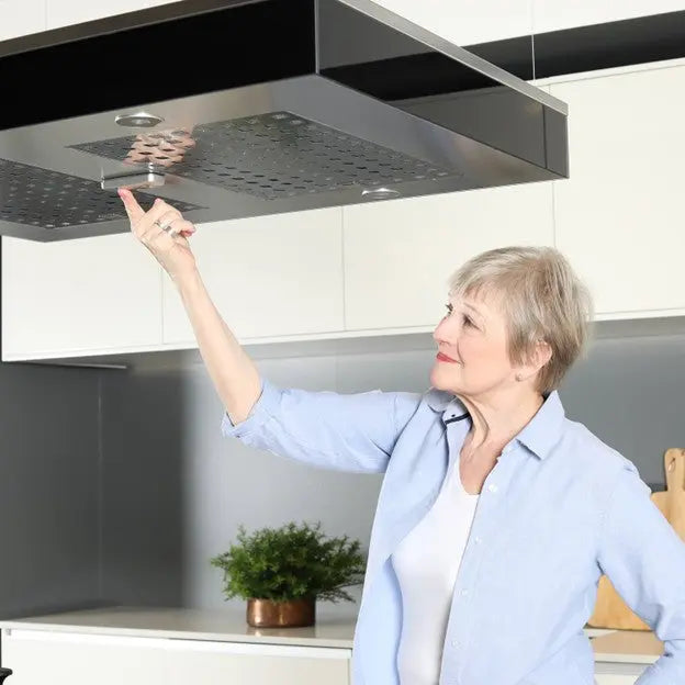 Woman adjusting a kitchen exhaust hood in a modern kitchen.